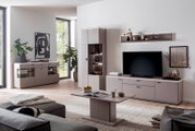 Modernes Wohnzimmer mit beigefarbener Wohnwand: TV-Lowboard, Vitrine und Sideboard mit Glasfächern und LED-Beleuchtung, dazu passender Couchtisch; Aufnahme aus leicht erhöhter, frontaler Perspektive.