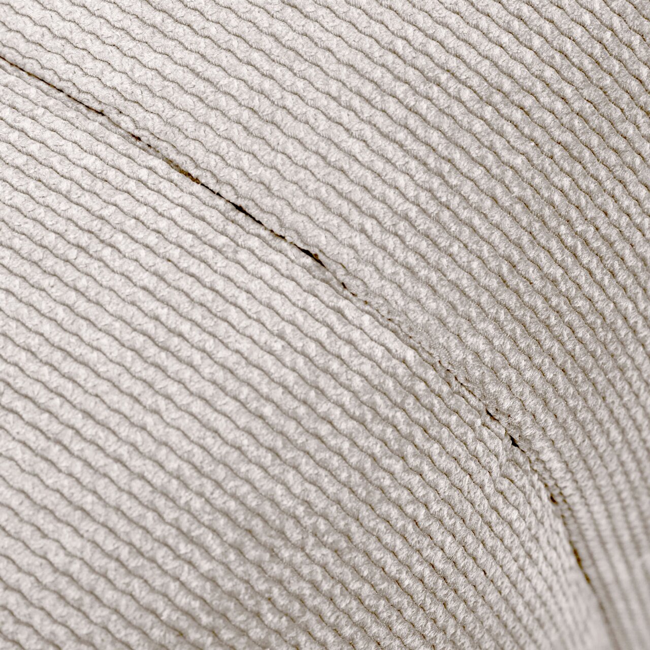 Nahaufnahme eines Hockers mit strukturierter, hellgrauer Stoffoberfläche, seitliche Perspektive