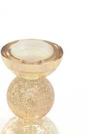 Champagnekleurige glazen kandelaar met bolvormige voet vol decoratieve luchtbelletjes, van voren en licht van boven gefotografeerd