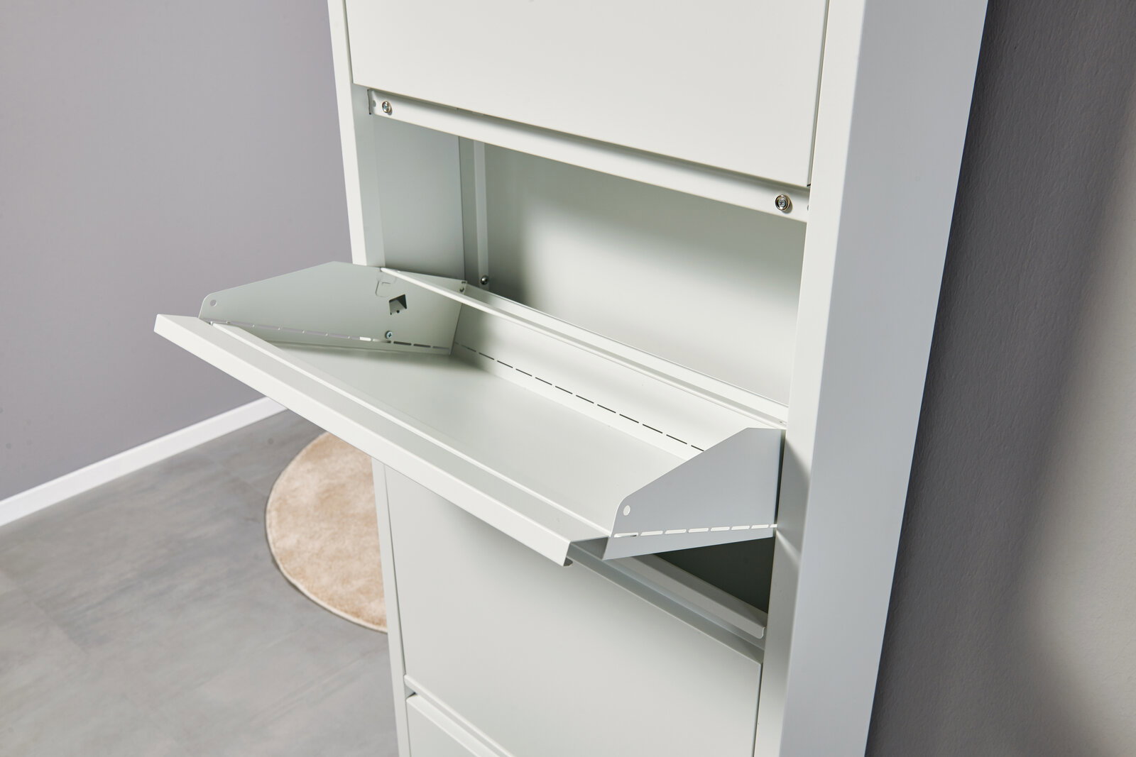 Weißer Metallschrank mit geöffneter Klapptür/Schreibklappe und Ablagefach, schräg von vorne rechts fotografiert.