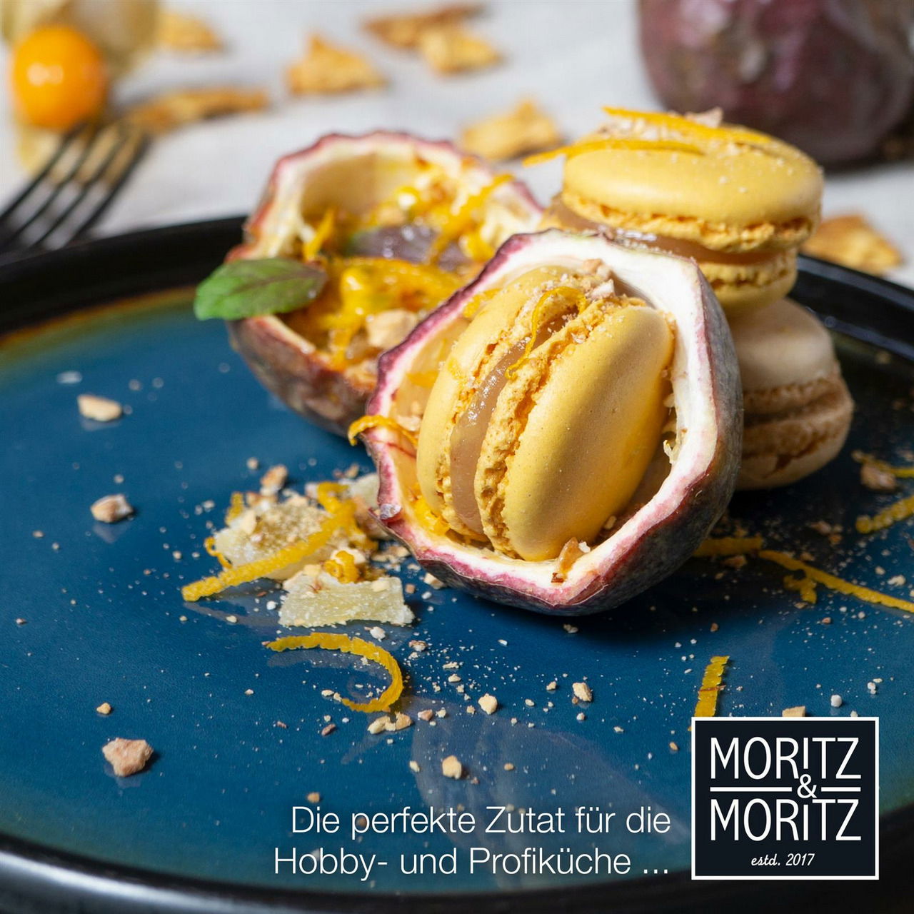 Nahaufnahme eines blauen Desserttellers mit gelben Macarons und Passionsfrucht, dekoriert mit Orangenschalen und Nüssen.