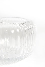 Nahaufnahme eines transparenten, bauchigen Glasgefäßes mit vertikaler Rillenstruktur, aus leicht erhöhter seitlicher Perspektive vor weißem Hintergrund