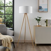 Moderne Stehleuchte mit dreibeinigem Holzgestell und weißem Lampenschirm, seitliche Perspektive im Wohnzimmer.