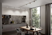 Moderne Küche mit Schienenpendel Aldan, hängend über einem Esstisch, mit Blick auf große Fenster und graue Küchenschränke.