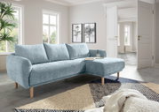 Helles, modernes Ecksofa in einem Wohnzimmer mit großen Fenstern, aus hellblauem Stoff und Holzbeinen, von vorne rechts betrachtet.