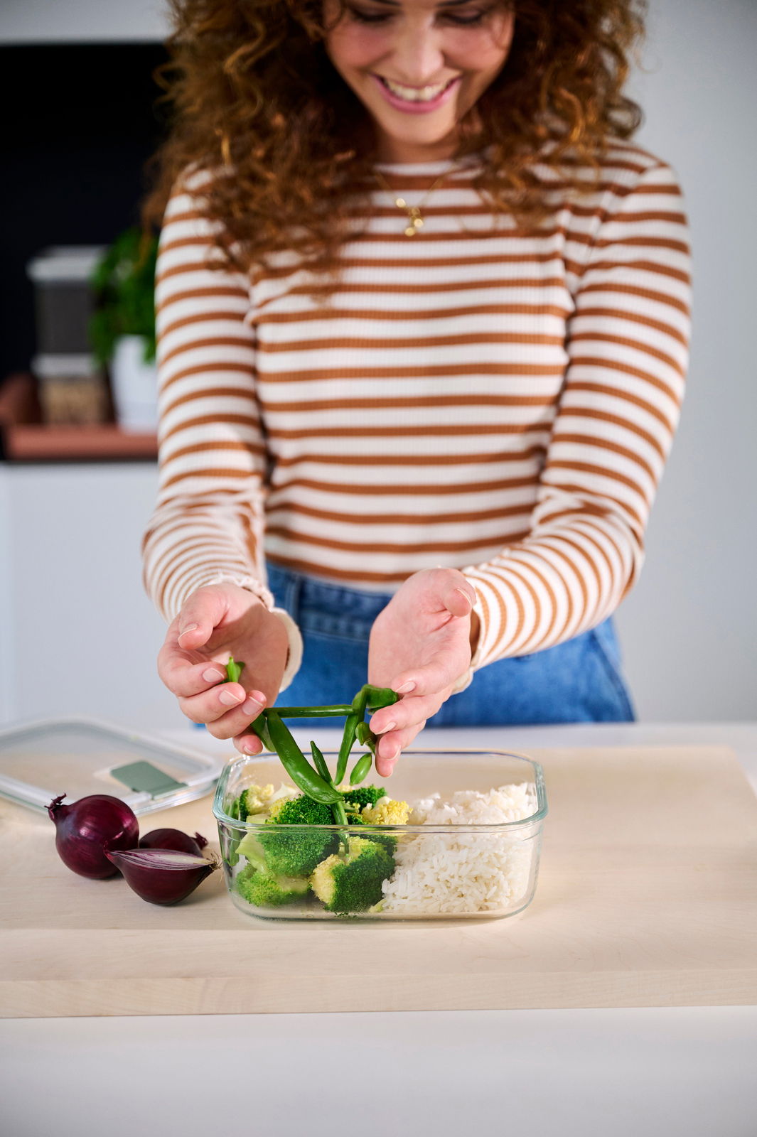 Mepal Glas Frischhaltedose Nordic sage EASYCLIP Frau füllt eine Glas-Frischhaltedose mit Gemüse und Reis, Ansicht von vorne.