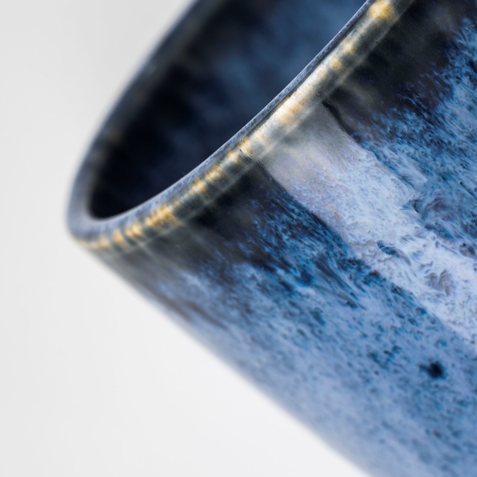 Detailaufnahme einer blau marmorierten Keramikschale mit glänzender Glasur, schräg von oben auf den Rand fotografiert