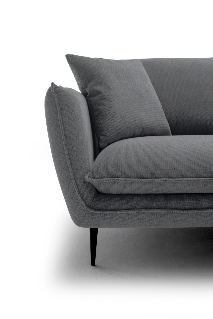 Nahaufnahme eines grauen Stoffsofas mit Armlehne, Sitzkissen und Rückenkissen auf schwarzen, schlanken Füßen, Ansicht schräg von vorne links.