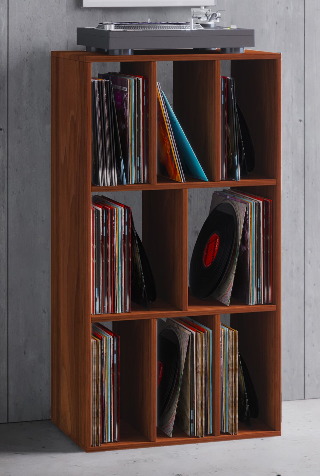 Holzfarbenes Schallplattenregal mit sechs Fächern, gefüllt mit Vinyl-LPs, mit Plattenspieler obenauf vor grauer Wand, frontale leicht seitliche Perspektive