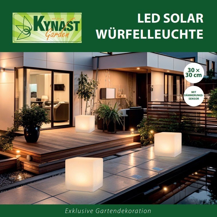 Kynast Exclusive Solar Würfelleuchte Solar Würfelleuchte 30x30cm auf einer Terrasse bei Nacht, leuchtend und umgeben von Pflanzen, mit moderner Architektur im Hintergrund.