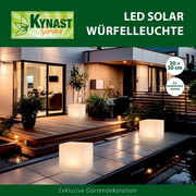 Solar Würfelleuchte 30x30cm auf einer Terrasse bei Nacht, leuchtend und umgeben von Pflanzen, mit moderner Architektur im Hintergrund.
