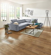 Graues Ecksofa MAROLA in modernem Wohnzimmer, seitliche Perspektive mit Holzboden und großen Fenstern.