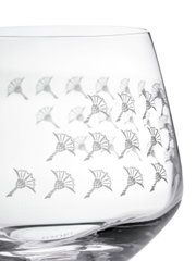 Nahaufnahme eines Wasserglases mit dekorativem Muster aus stilisierten Blumen, seitliche Perspektive.