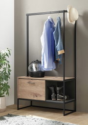 Moderne Garderobe mit schwarzem Metallrahmen, Holzablage, Kleiderstange mit Hemd und Jacke, sowie Stauraum für Helm und Schuhe. Seitliche Perspektive.