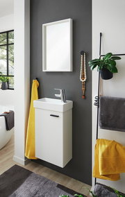 Modernes Gästebad mit weißem Waschbeckenunterschrank, gelbem Handtuch und Spiegel, seitliche Perspektive