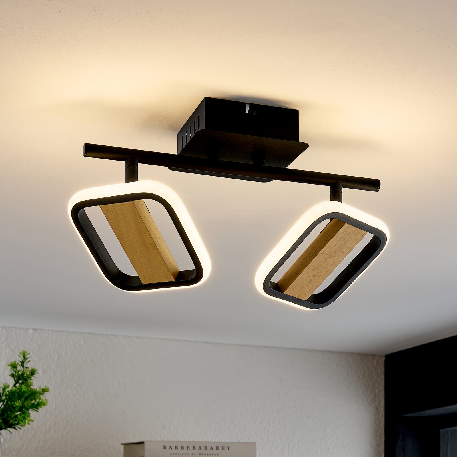 Novel LED-Strahler STRAHLER Moderne LED-Deckenleuchte mit zwei rechteckigen, schwarz umrandeten Strahlern und Holzelementen, von unten betrachtet.