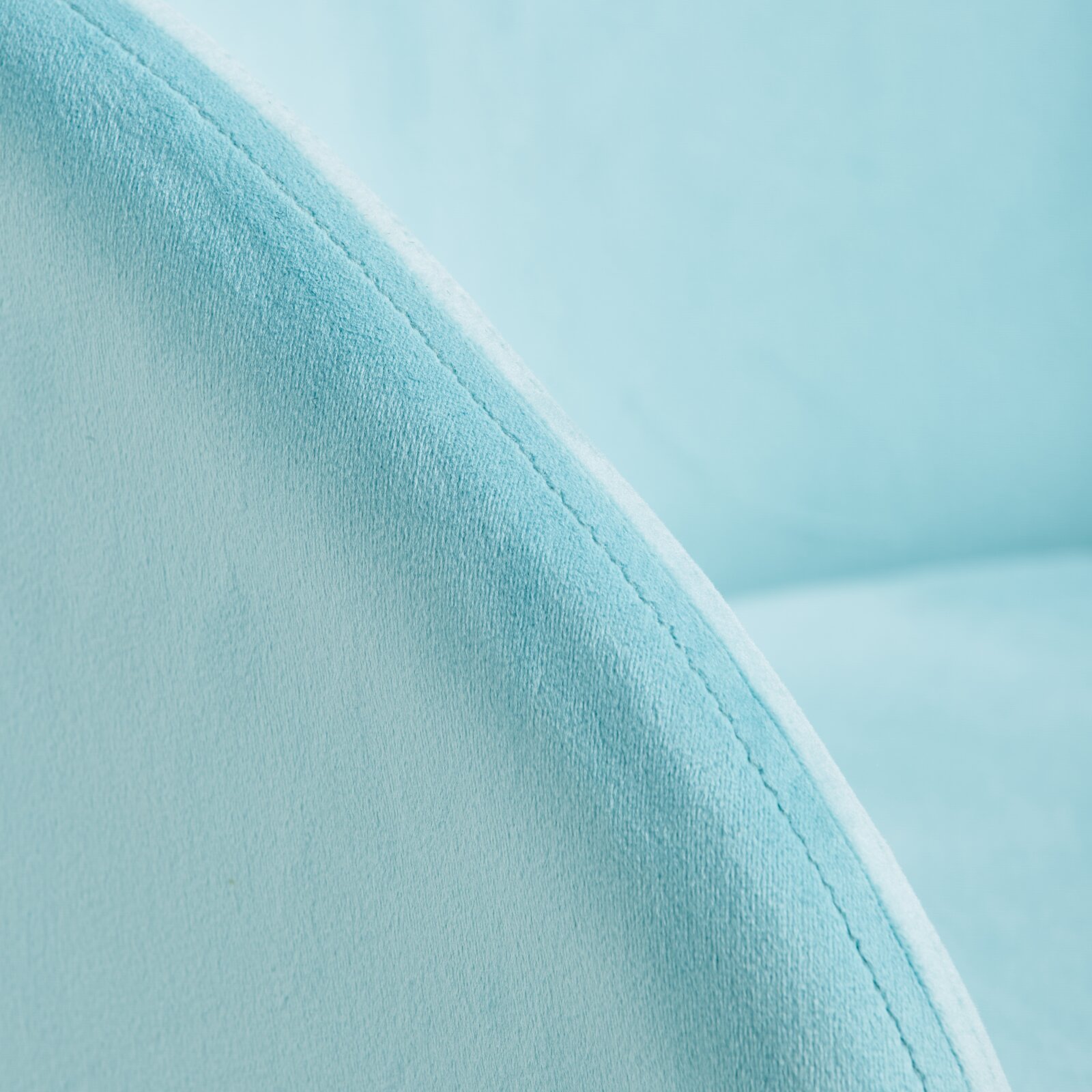 Close-up van een lichtblauwe fauteuil met een zachte textuur, met de nadruk op de naad van de armleuning.