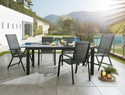 Moderner Gartentisch Ambia TERUEL mit vier Stühlen auf einer Terrasse, im Hintergrund ein Pool und Berge, seitliche Perspektive.