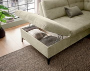 Ecksofa mit Stauraum, geöffnet, aus seitlicher Perspektive, in einem modernen Wohnzimmer mit Holzboden und großem Fenster.