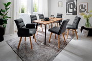 Moderner Esstisch mit Holzplatte und schwarzen Metallbeinen, umgeben von sechs grauen Polsterstühlen auf einem gemusterten Teppich in einem hellen Raum. Perspektive: seitlich von vorne.