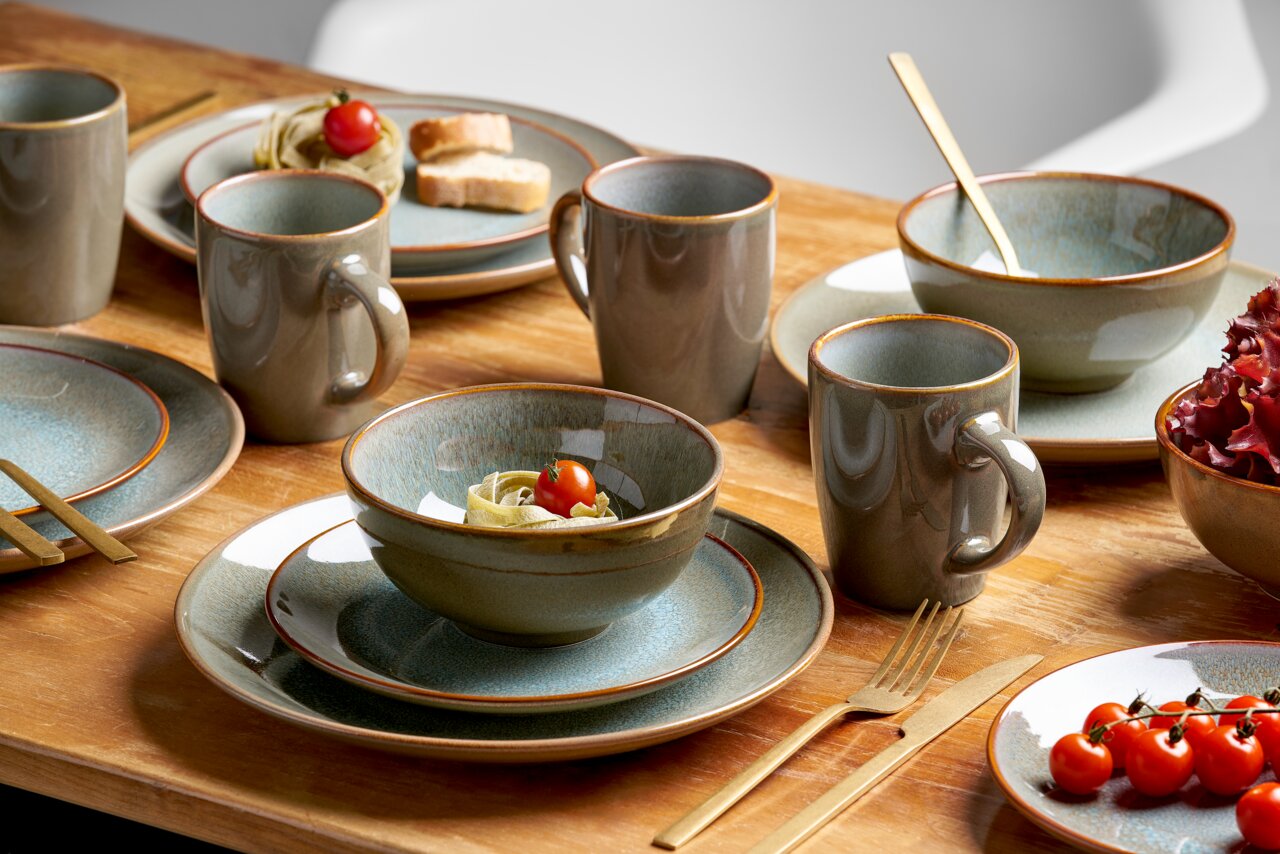Kombiservice 16-tlg. in einer stilvollen Tischdekoration, bestehend aus Tellern, Schalen und Tassen in Erdtönen, auf einem Holztisch von schräg oben fotografiert.