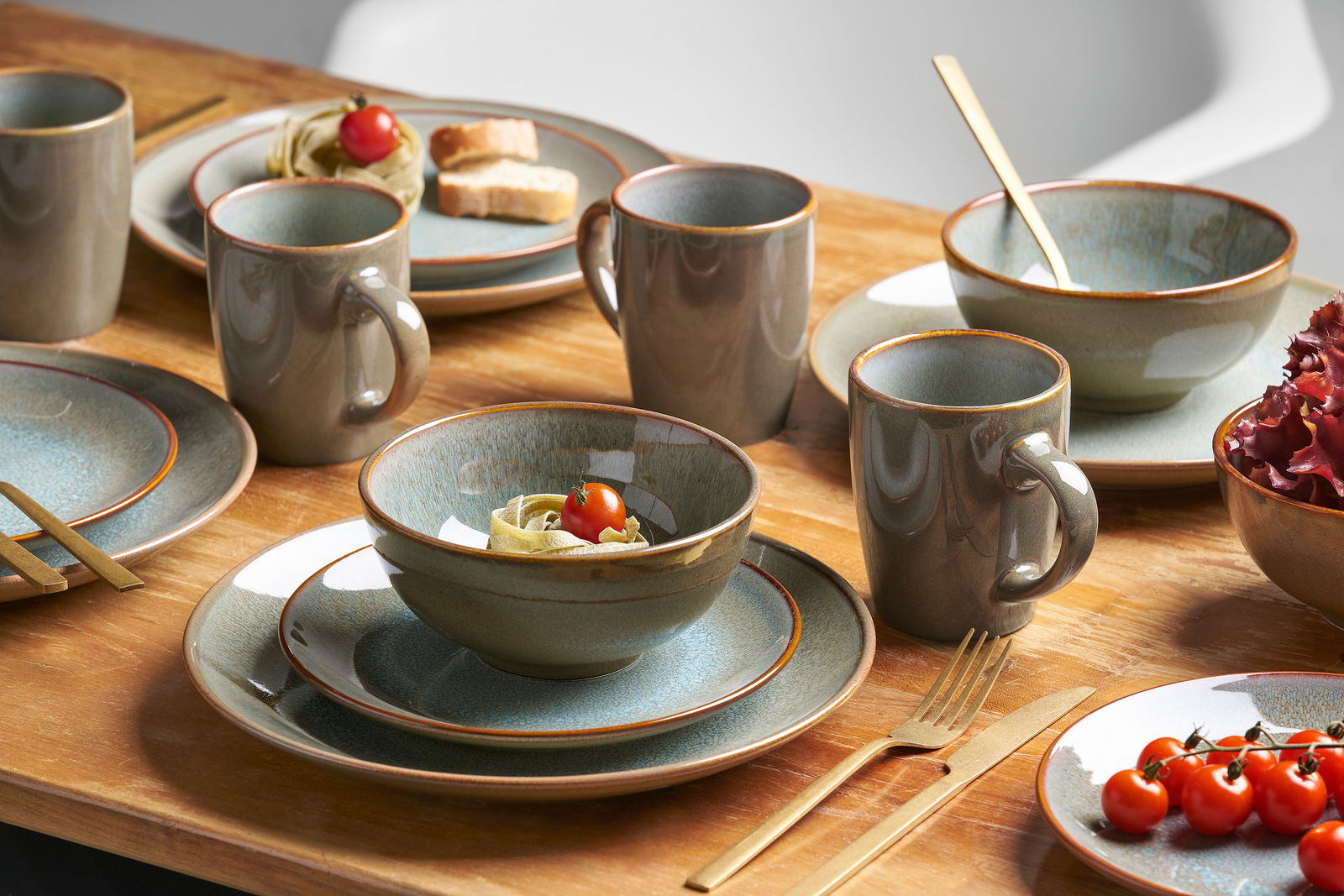 Kombiservice 16-tlg. in einer stilvollen Tischdekoration, bestehend aus Tellern, Schalen und Tassen in Erdtönen, auf einem Holztisch von schräg oben fotografiert.