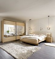 Moderner Schwebetürenschrank mit zwei Türen in Holzoptik, mit Spiegeln versehen, in einem stilvoll eingerichteten Schlafzimmer. Perspektive: Frontalansicht.