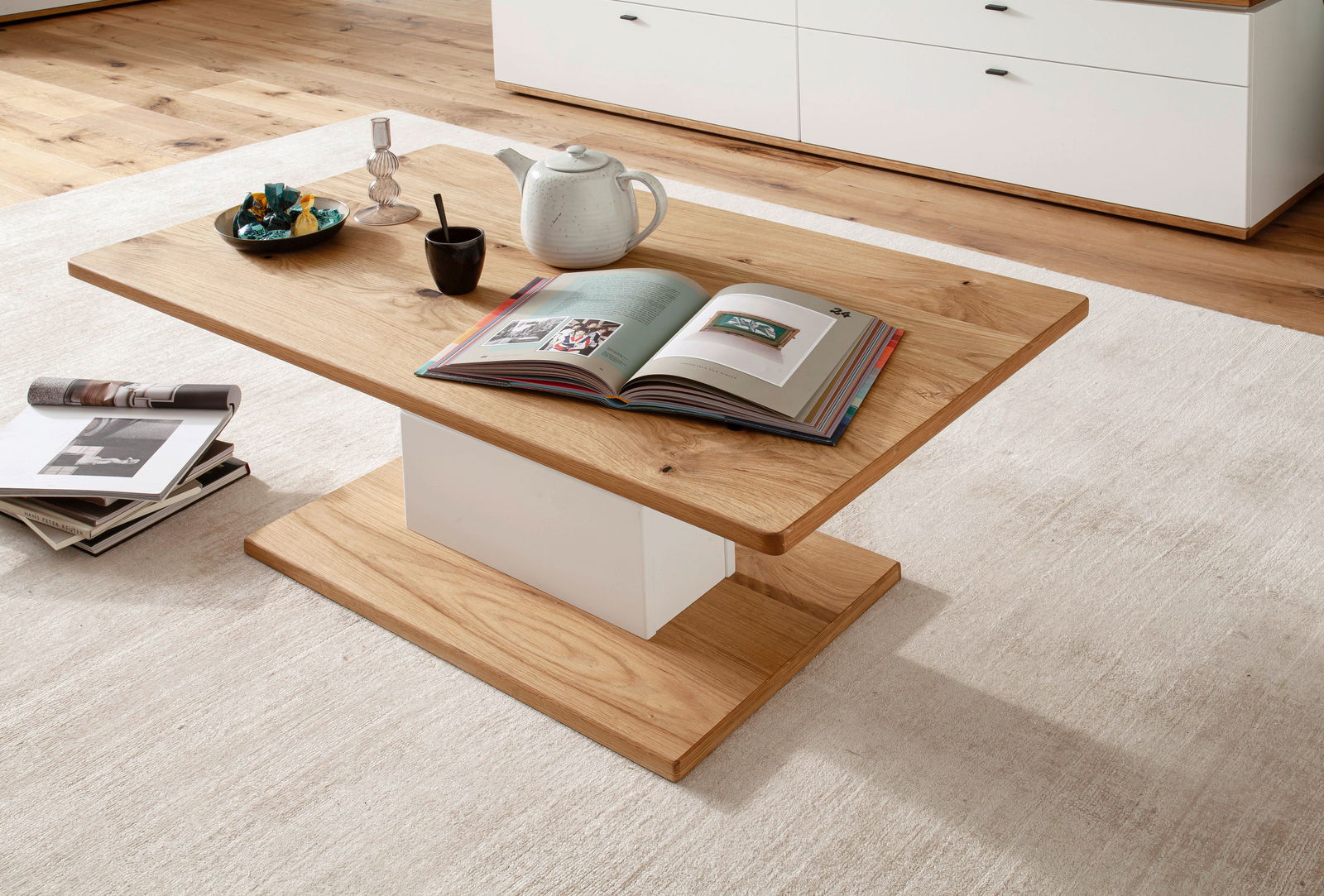 Novel Couchtisch MATADI Moderner Couchtisch aus Holz mit weißem Sockel, dekoriert mit Büchern, einer Teekanne und einer Schale, aus der Perspektive von schräg oben fotografiert.