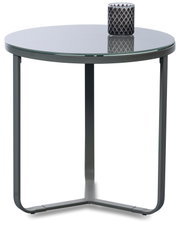 Runder Beistelltisch mit Glasplatte und dunkelgrauem Metallgestell, frontale Ansicht leicht von oben; auf der Tischplatte steht ein dunkler Kerzenhalter.