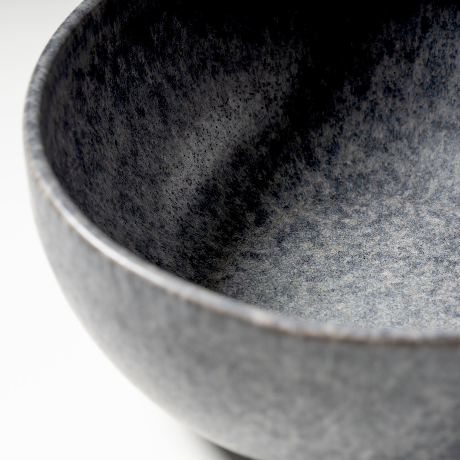 Detailaufnahme einer graublauen, gesprenkelten Keramikschale mit sichtbarer Innenfläche und Rand, fotografiert aus schräger Draufsicht
