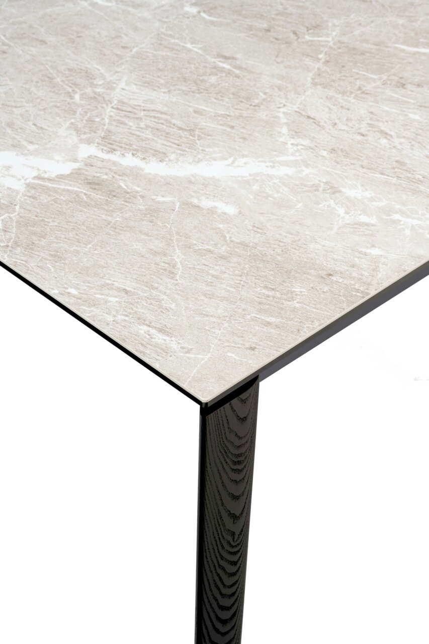 Connubia Esstisch BAND Nahaufnahme eines Esstisches mit heller Marmoroptik und dunklem Holzbein, aus der Perspektive von oben.