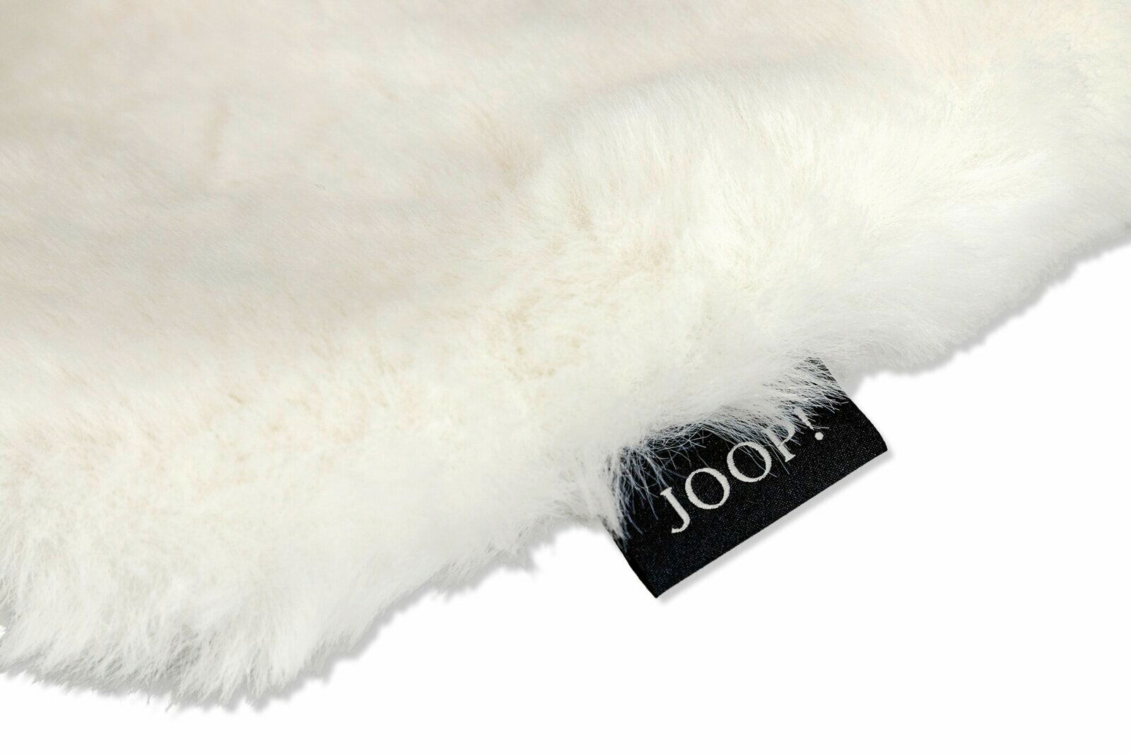 Nahaufnahme eines flauschigen weißen Stoffes mit einem schwarzen Etikett, auf dem 'JOOP!' steht. Perspektive von oben.