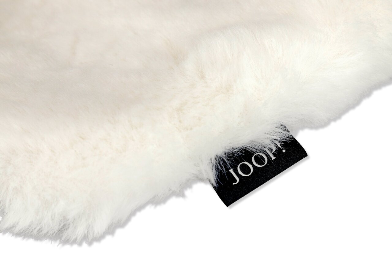 Nahaufnahme eines flauschigen weißen Stoffes mit einem schwarzen Etikett, auf dem 'JOOP!' steht. Perspektive von oben.