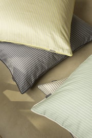 Blick von oben auf gestreifte Bettwäsche in verschiedenen Farben: Gelb, Grau, Grün und Weiß.