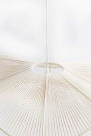 Nahaufnahme einer Hängeleuchte mit einem weißen, fächerförmigen Design aus gespannten Fäden, von unten betrachtet.