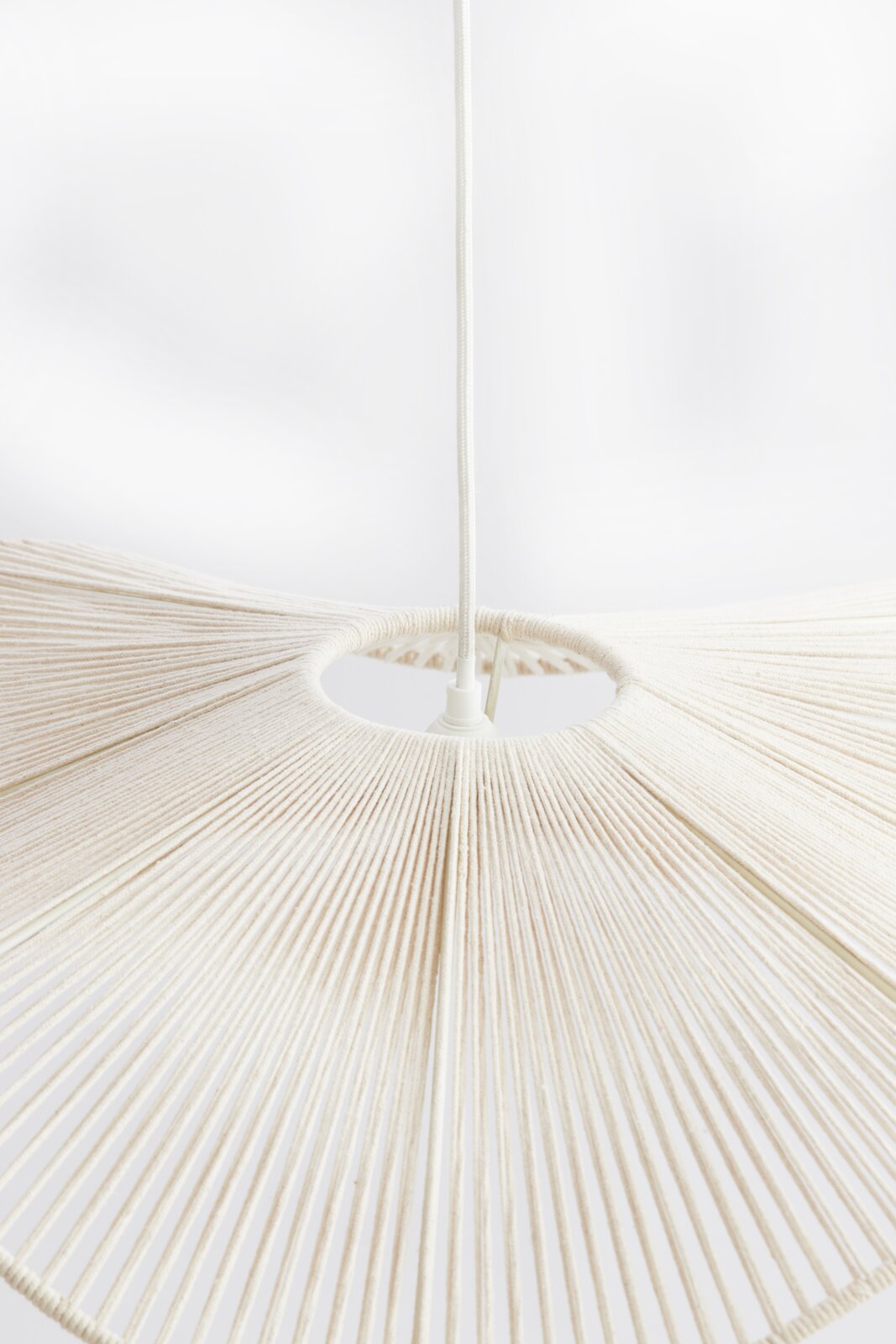 Close-up van een hanglamp met een wit, waaiervormig ontwerp van gespannen draden, gezien van onderaf.