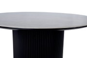 Moderne salontafel met een rond, glad blad en een geribbeld, zwart onderstel, gezien vanaf de zijkant