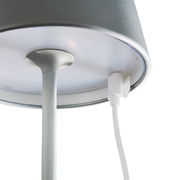 Nahaufnahme der Unterseite einer Akku-Tischleuchte COSENZA mit Ladeanschluss und Kabel, von unten betrachtet.