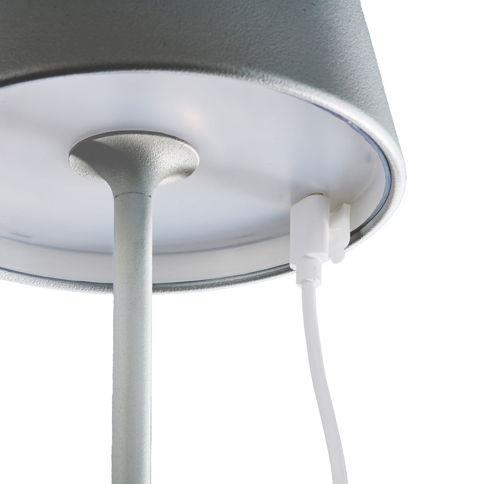 Nahaufnahme der Unterseite einer Akku-Tischleuchte COSENZA mit Ladeanschluss und Kabel, von unten betrachtet.