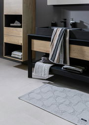 Moderne Badezimmeransicht mit schwarzer Mischbatterie und Waschbecken, umgeben von Holz- und Metallelementen, mit Handtüchern und Badteppich. Perspektive von schräg vorne.