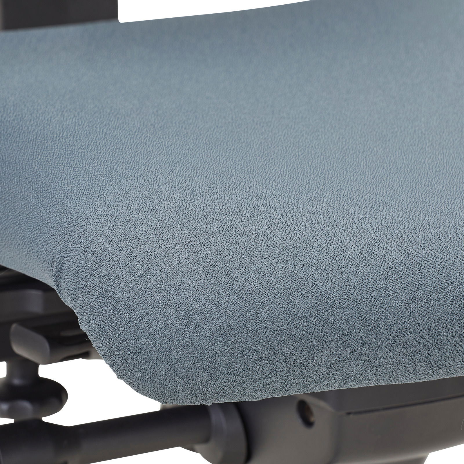 Nahaufnahme der Sitzfläche eines Drehstuhls mit grauem Stoffbezug, seitliche Perspektive.