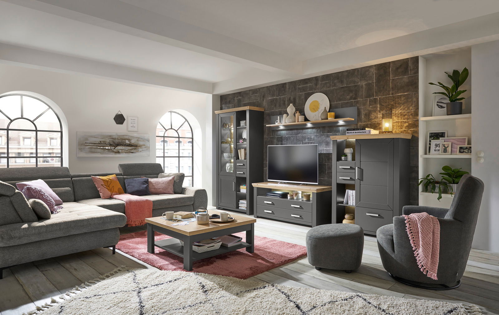 Moderne Wohnwand in einem stilvollen Wohnzimmer mit grauen Möbeln, einem großen Sofa, einem Couchtisch und dekorativen Elementen, seitliche Perspektive.