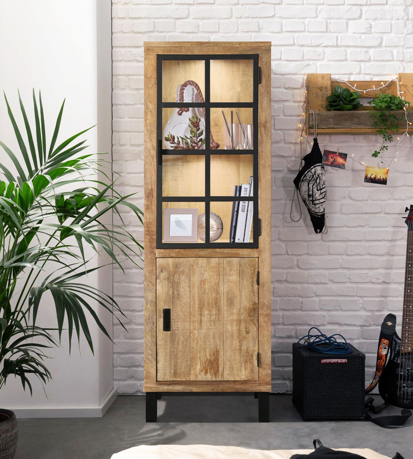 Holzvitrine mit Glastür und schwarzem Rahmen, frontal fotografiert, dekoriert mit Büchern und Pflanzen, in einem modernen Raum mit weißer Backsteinwand.