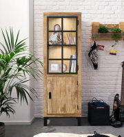Houten vitrinekast met glazen deur en zwart frame, gefotografeerd van voren, versierd met boeken en planten, in een moderne ruimte met een witte bakstenen muur.