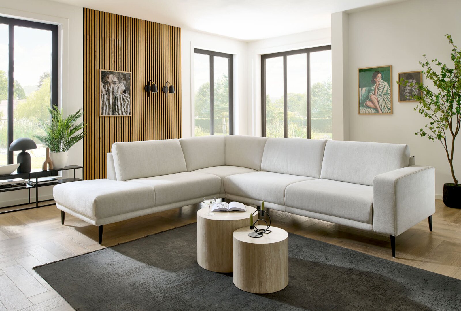 Dieter Knoll Hoekbank MORINO 2.0 Moderne hoekbank in lichtbeige, in een stijlvol ingerichte woonkamer met houten vloer en grote ramen, gefotografeerd vanuit een licht zijdelingse hoek.