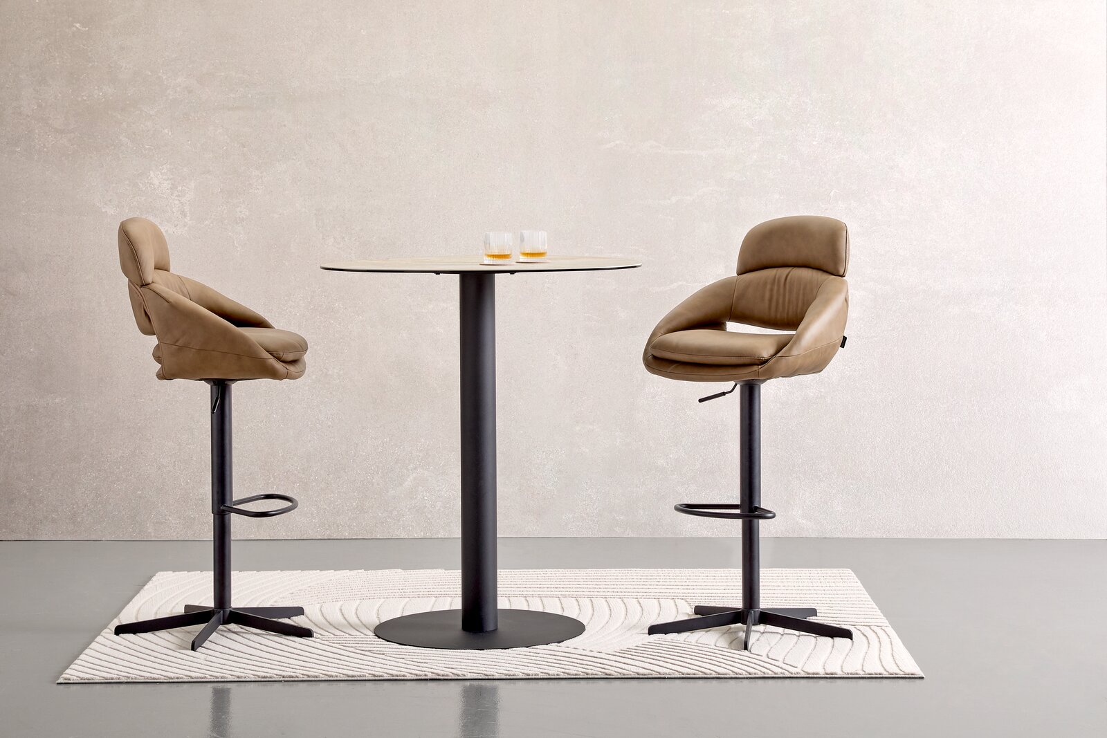 Moderner Bartisch mit zwei beigen Barhockern, seitliche Perspektive