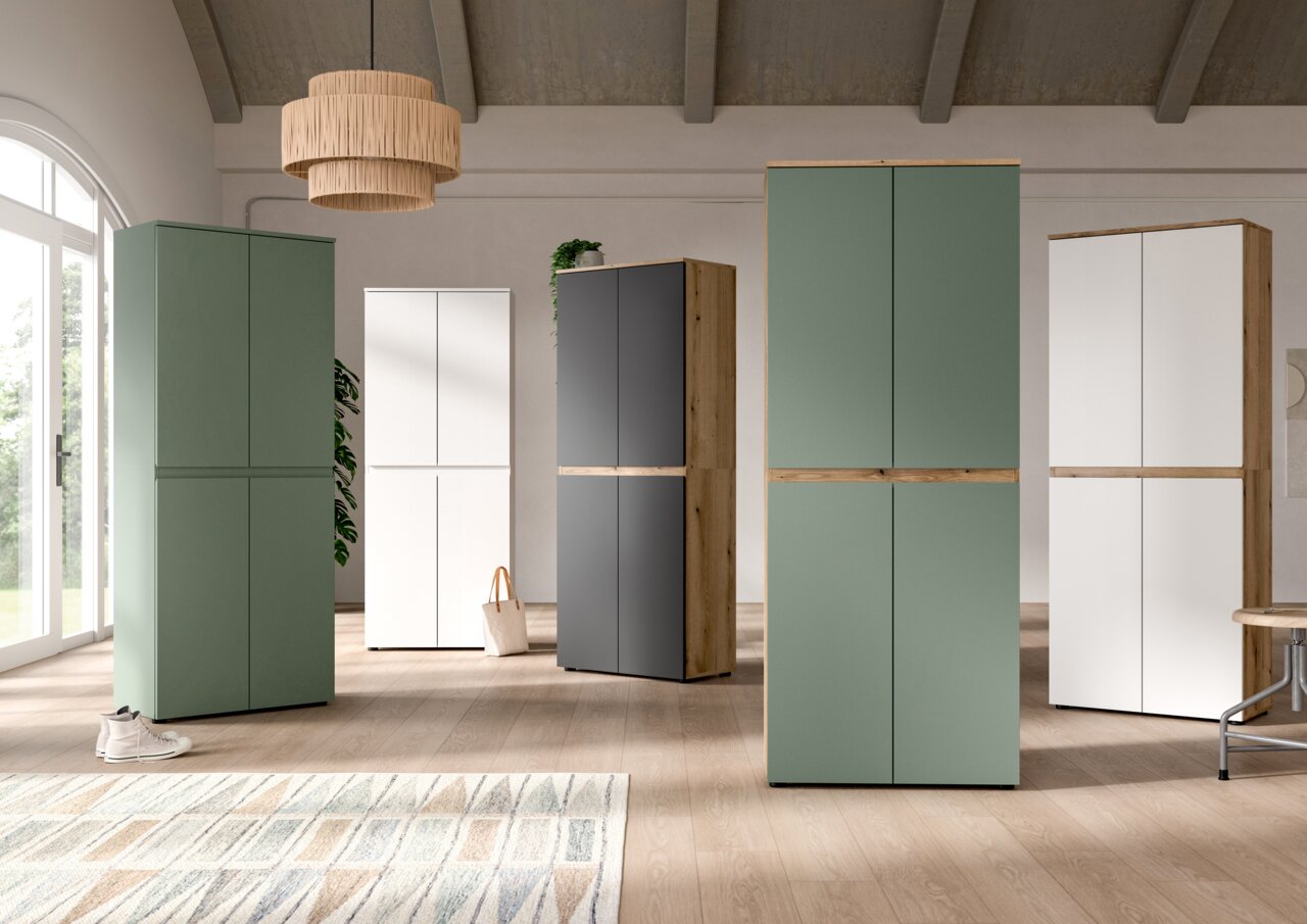 Moderne, hohe Schränke mit glatten Fronten in Grün, Weiß und Anthrazit mit Holzdetails in einem hellen Wohnraum, frontale Perspektive auf die Möbelgruppe.