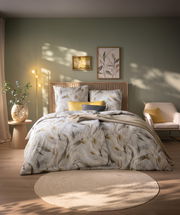 Gemütliches Schlafzimmer mit stilvoller Bettwäsche in sanften Naturtönen, dekoriert mit Pflanzen und Kunstwerken, aus der Vorderansicht.