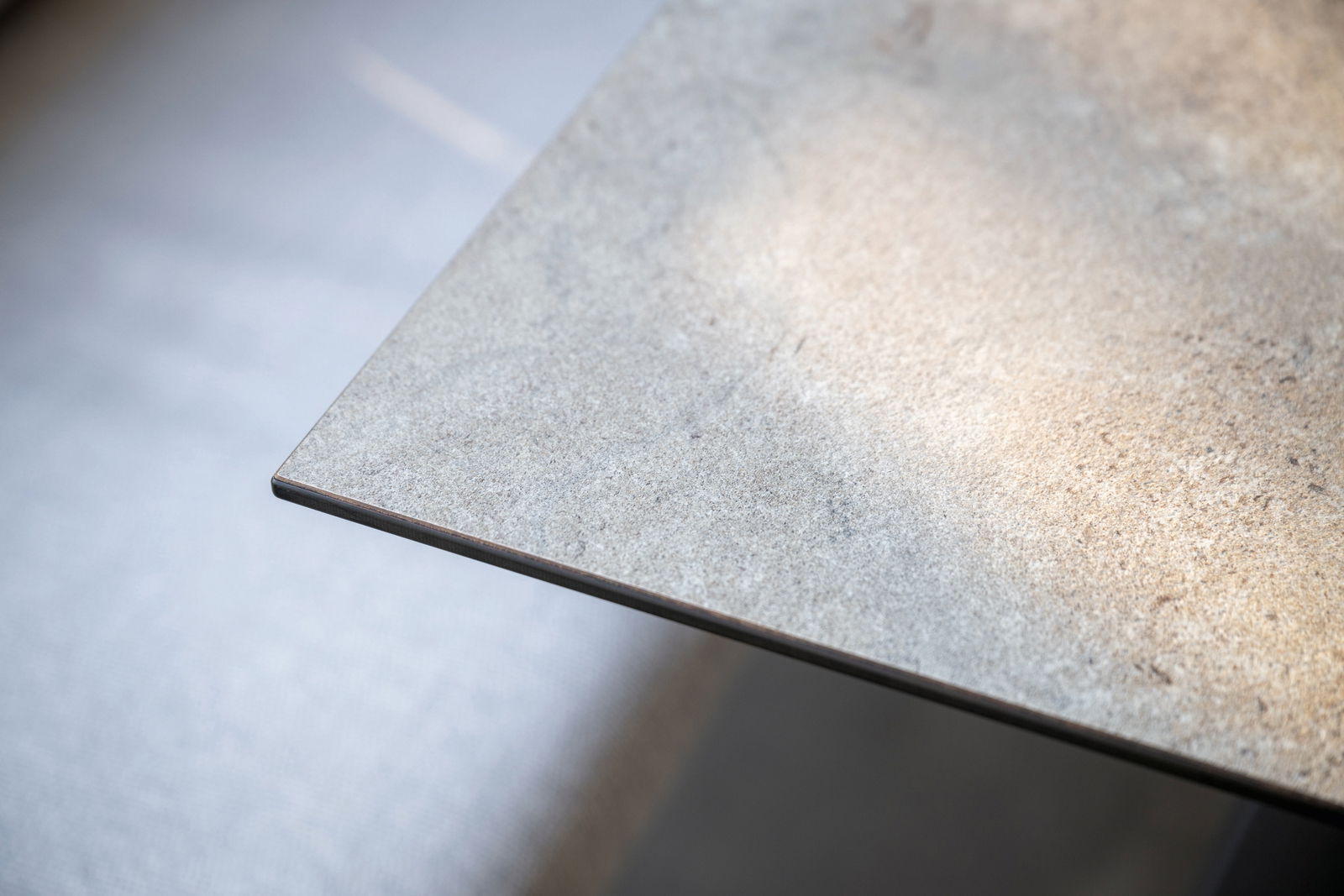 Nahaufnahme einer Ecke eines Gartentisches mit glatter, steinartiger Oberfläche, von oben betrachtet.