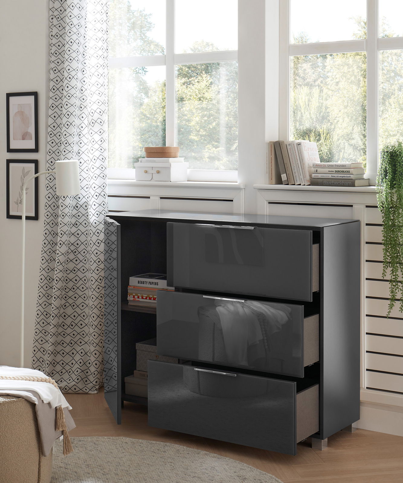 Moderne Kommode mit glänzender schwarzer Oberfläche, drei Schubladen und einer offenen Tür, seitliche Perspektive